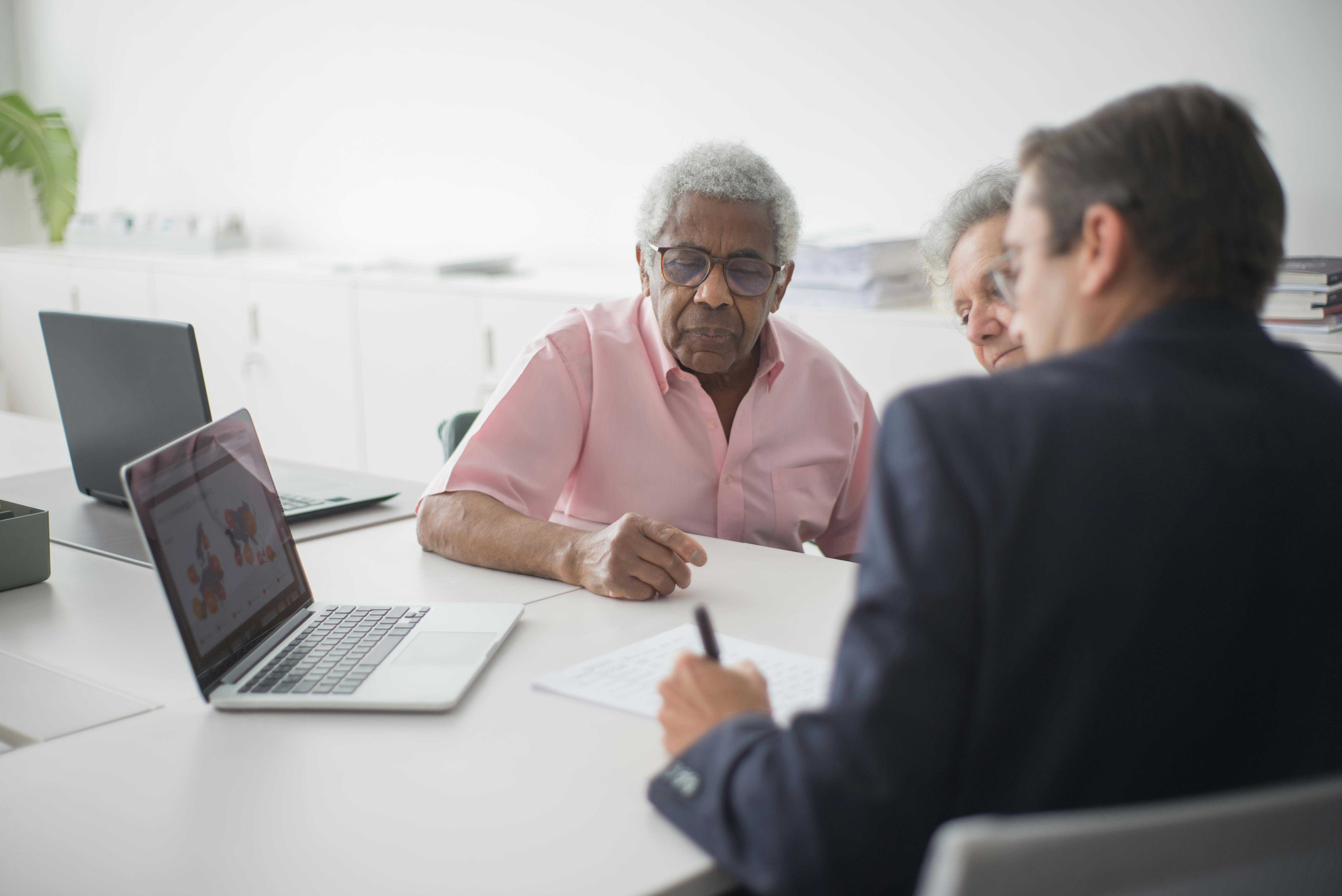 A senior woman smiling with her adult daughter, reviewing insurance paperwork together at a kitchen table